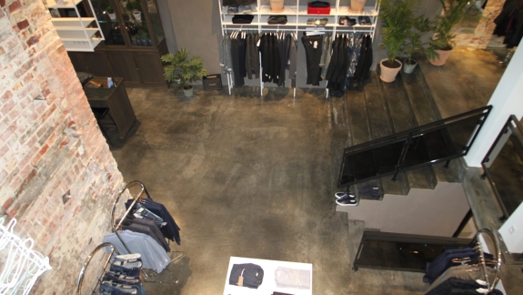 Butik med rå murstensvæg og epoxy gulv udført af PerBro Gulve i Kolding. Industrielt look med moderne tøjdisplay.