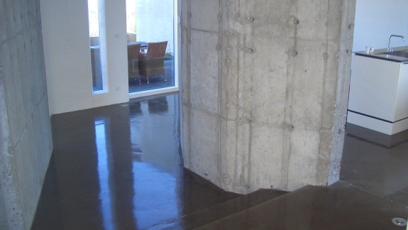 Højglans epoxy gulv omkring rå betonsøjle, udført af PerBro Gulve i Kolding. Moderne og rå arkitektur.