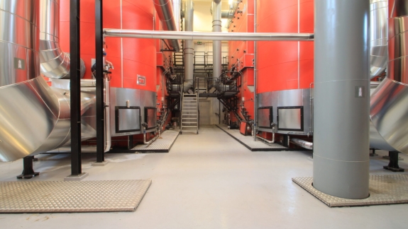 Industrigulv med lysegrå epoxy, udført af PerBro Gulve i Kolding. Store røde kedelanlæg og stålrør i produktion.